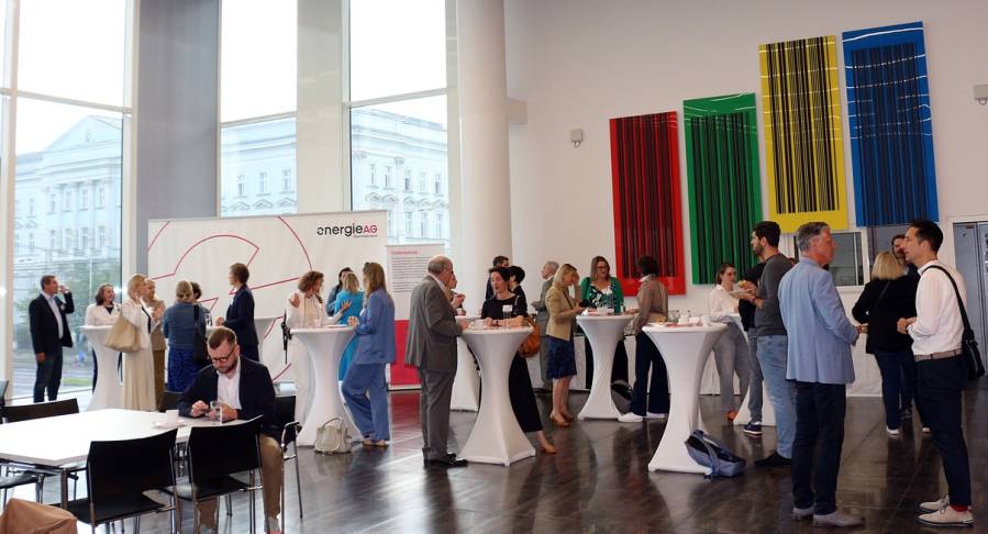 Teilnehmende unterhalten sich bei Stehtischen im Veranstaltungsraum